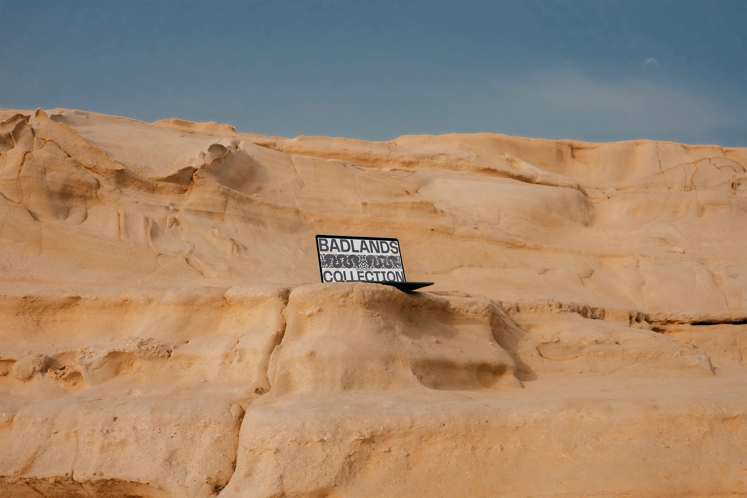 Laptop placed on a sand/orange color rocks.