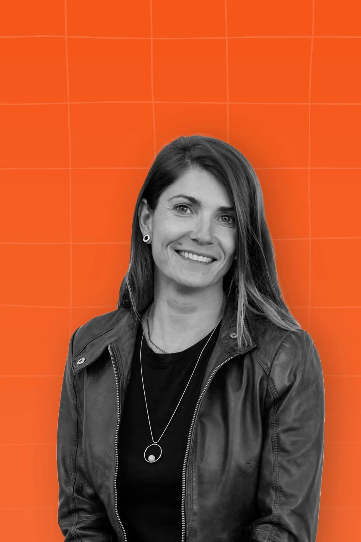 Black and white portrait of a woman wearing a leather jacket placed on orange background with light orange pattern.